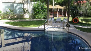 Ein Swimmingpool mit glasklarer, blauer Wasseroberfläche, umgeben von einem gepflegten Rasen und einigen Liegestühlen.