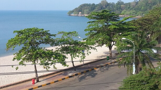 A coastal road with a beach and a small island in the distance. - Bird of Paradise Bungalows (Kep)