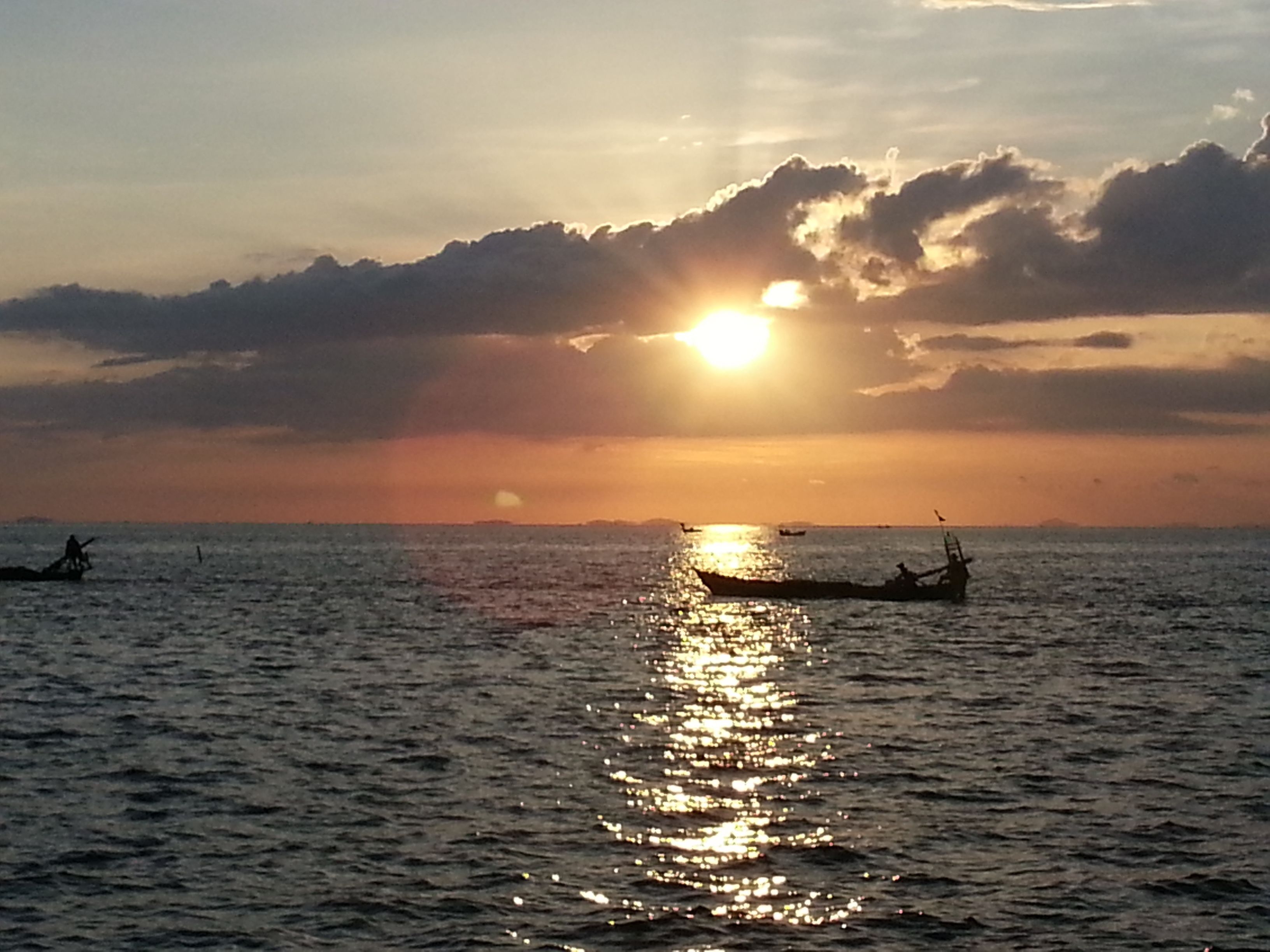 Un atardecer sobre un mar tranquilo con barcos.