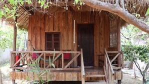 A wooden cabin with a porch, a door, and a small window. - Bird of Paradise Bungalows (Kep)