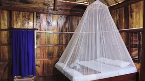 A wooden room with a bed under a mosquito net. - Bird of Paradise Bungalows (Kep)
