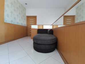 A small, circular, dark-colored seating area in a hallway with wooden paneling and a tiled floor. - Le Desir Resortel (Chalong)