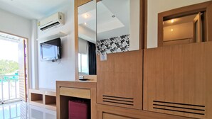 A hotel room with a wooden vanity, a mirror, a flat-screen TV, and a window with a view of the outside.