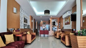A hotel lobby with seating areas, a reception desk, and a view of the hallway.