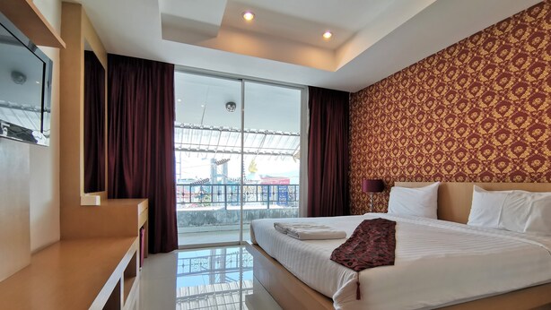 A modern hotel room with a large bed, a TV, and a balcony with a view.