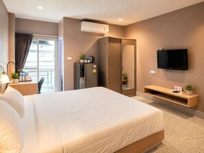 A hotel room with a bed, a TV, a minibar, a mirror, and a window with curtains. - The Fifth Residence Hotel (Bangkok)