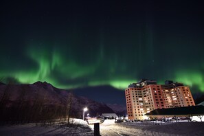 Un hotel con varios pisos, un estacionamiento y vistas a la aurora boreal.