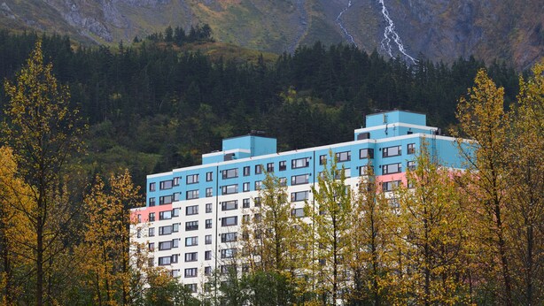 A multi-story hotel with a modern design, surrounded by autumn foliage and a mountainous backdrop. - Glacier View Condo Suites (Whittier)