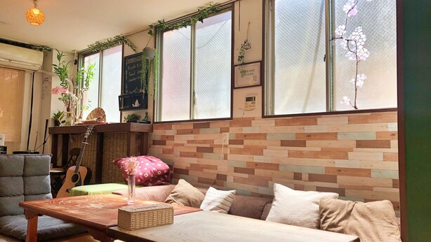 Una habitación acogedora con una mesa de madera, asientos con cojines y una guitarra.