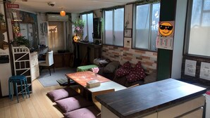 Un café acogedor y bien iluminado con suelo de madera, una mesa central y cojines morados.