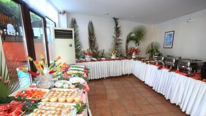Ein reichhaltiges Buffet mit verschiedenen Speisen und einem langen Tisch, bedeckt mit einer weißen Tischdecke.