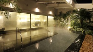 A modern indoor pool area with a glass enclosure, surrounded by palm trees and plants. - Hotel Emion Tokyo Bay (Urayasu)