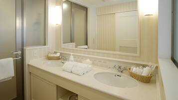 A hotel bathroom with two sinks, a large mirror, and a towel rack.