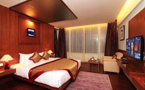 A hotel room with a large bed, a television, a desk, and a chair.
