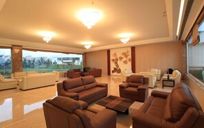 A spacious living room with leather sofas, a coffee table, and a large window offering a view of the outdoors.