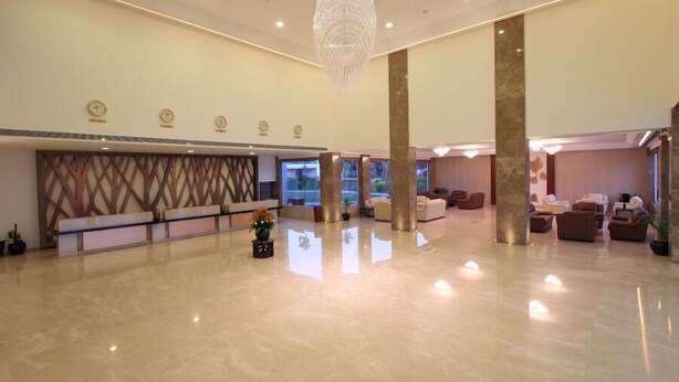 A spacious lobby with a reception desk, seating area, and a large chandelier. - Denissons (Hubli)