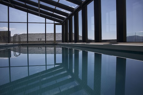 Una piscina techada, una piscina al aire libre de temporada, sombrillas