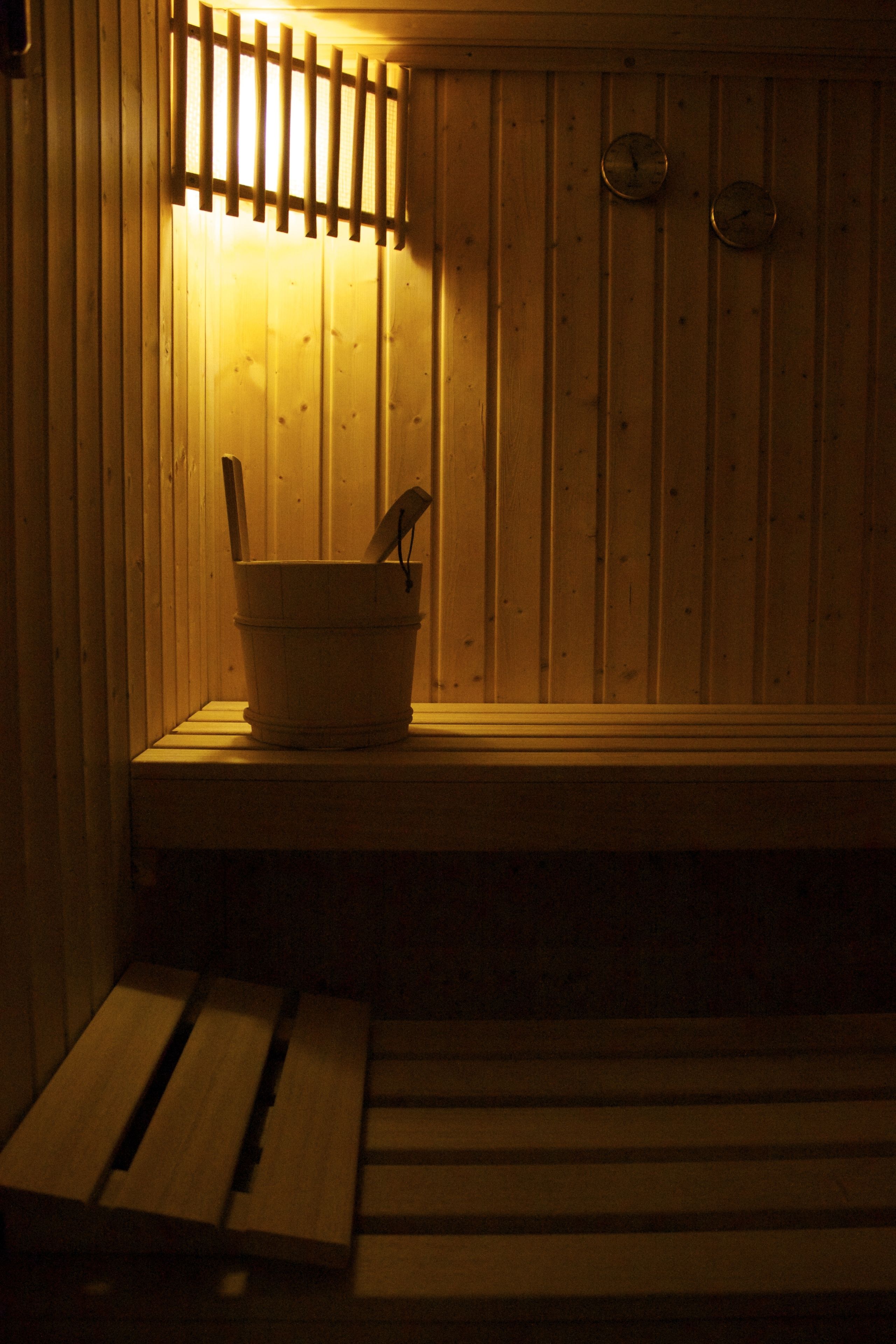 A wooden sauna with a bucket and a wooden bench.