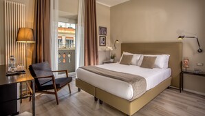 Une chambre d’hôtel avec un grand lit, un bureau, une chaise, une lampe et une vue sur l’extérieur.