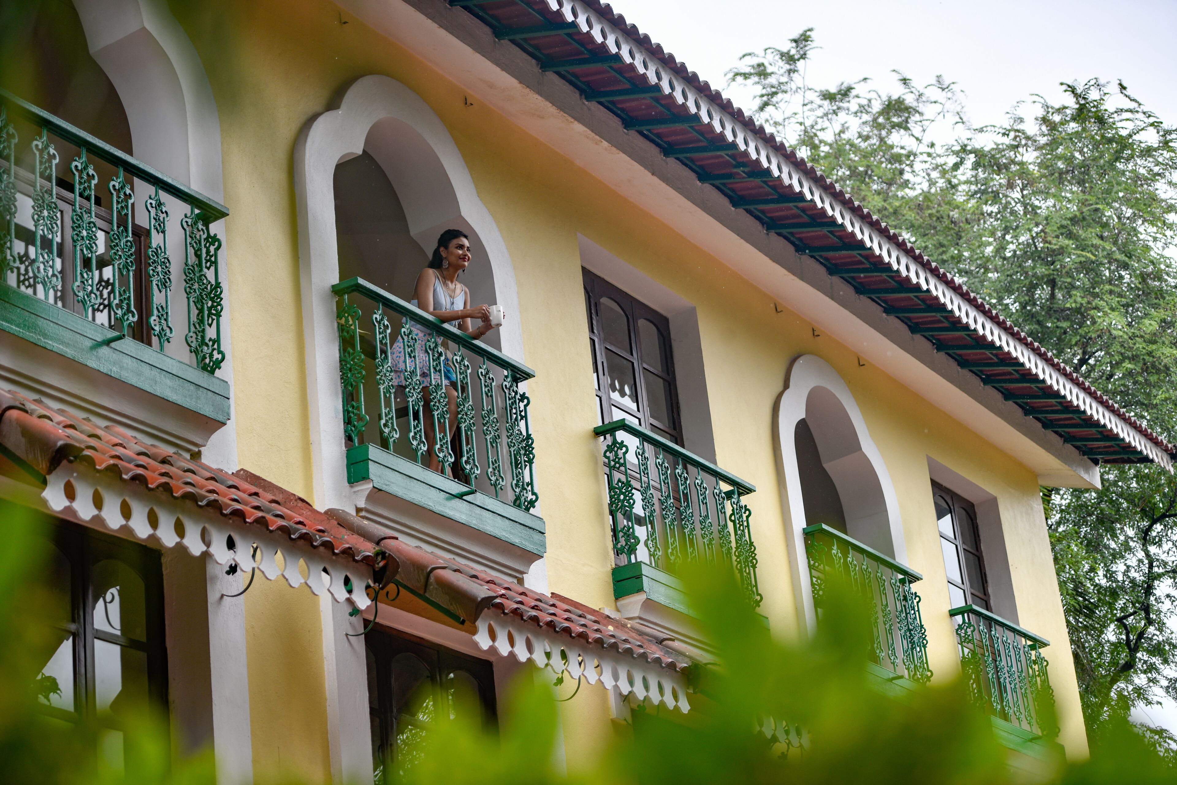 A building with multiple balconies, each with ornate green railings and a yellow facade.