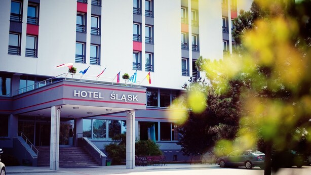 A modern hotel with a prominent entrance, multiple flags, and a well-maintained outdoor area.