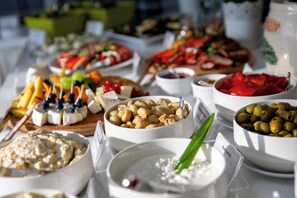 A buffet table with various food items including cheese, olives, and fruits.