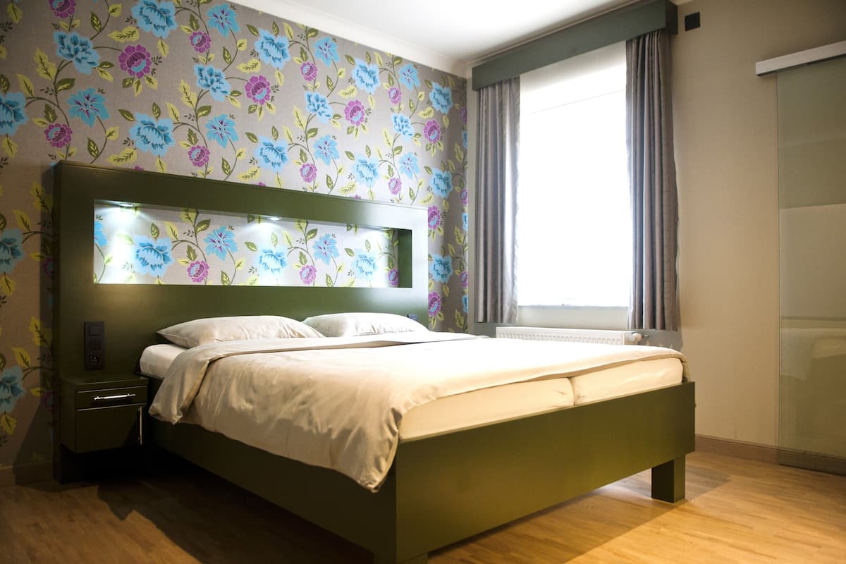 A bedroom with a bed, nightstand, and a window with curtains.
