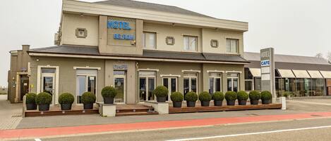 A hotel with a modern facade, multiple entry points, and a cafe sign.