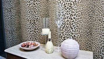 Una mesa con un cuenco de nueces, una vela y un florero frente a una pared con estampado de leopardo.