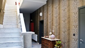 Een gang met een marmeren trap, een wand met luipaardprint, een houten dressoir en een deur.
