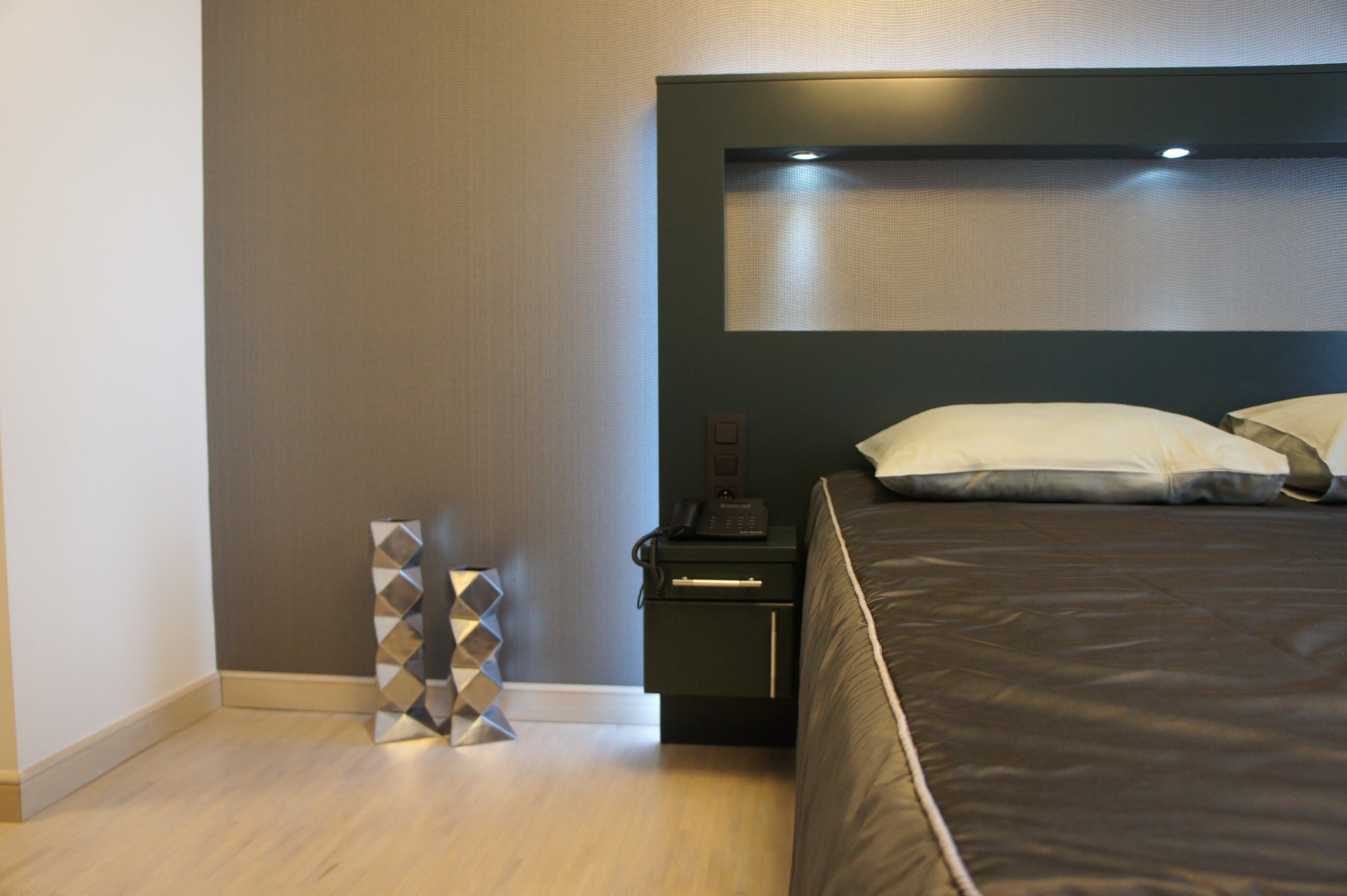 A modern bedroom with a bed, nightstand, and decorative wall piece.