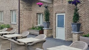 Een gebouw van baksteen met terras en plantenbakken.