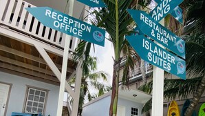 A beachside hotel with directional signs for amenities such as a reception office, restrooms, a restaurant & bar, and islander suites. - La Isla Resort (Caye Caulker)