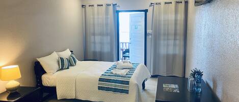 Une chambre d’hôtel avec un lit, un bureau, une lampe et une vue sur l’extérieur.
