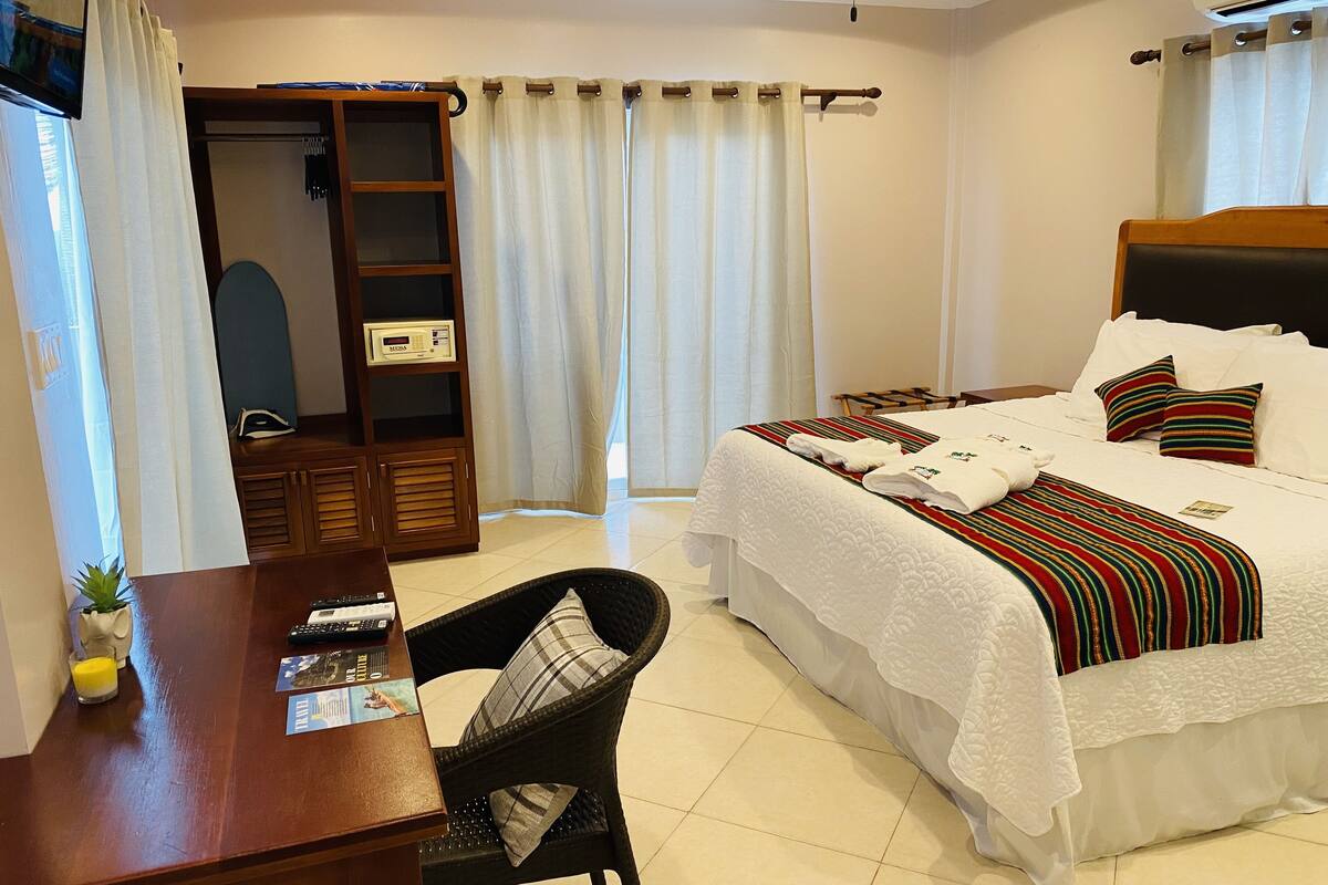 A hotel room with a bed, a desk, a chair, a wardrobe, and a television.