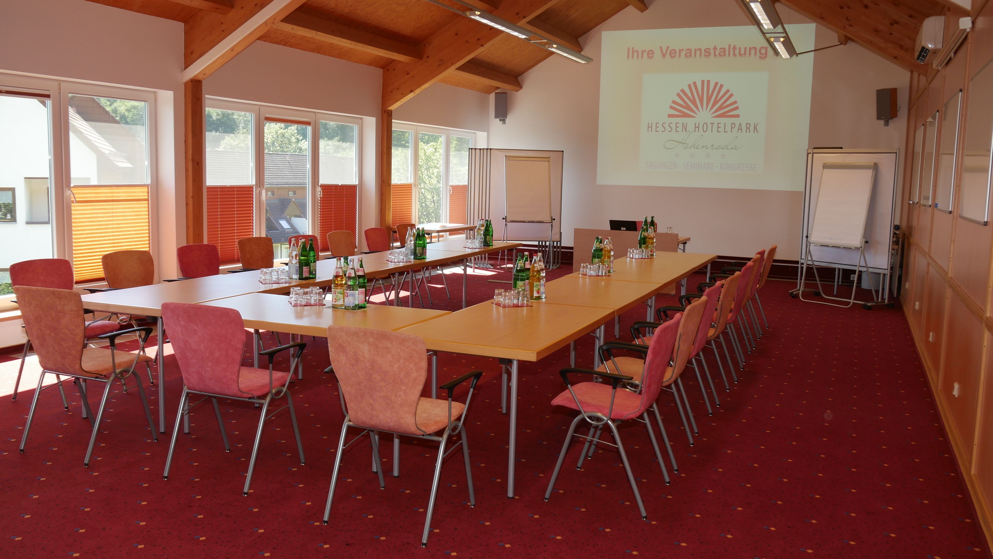 Une salle de conférence équipée d’une longue table, de chaises et d’un écran de présentation.