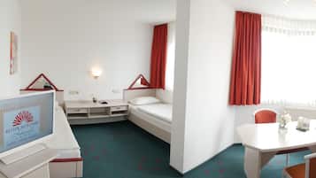A hotel room with a bed, a desk, a chair, a TV, and a window with curtains.