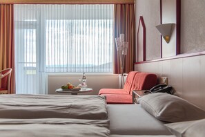 A hotel room with a bed, a chair, a table with fruit and a bottle, and a telephone. - Hessen Hotelpark Hohenroda (Hohenroda)