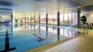 An indoor swimming pool with clear water, tiled walls, and a sunlit area with lounge chairs. - Hessen Hotelpark Hohenroda (Hohenroda)