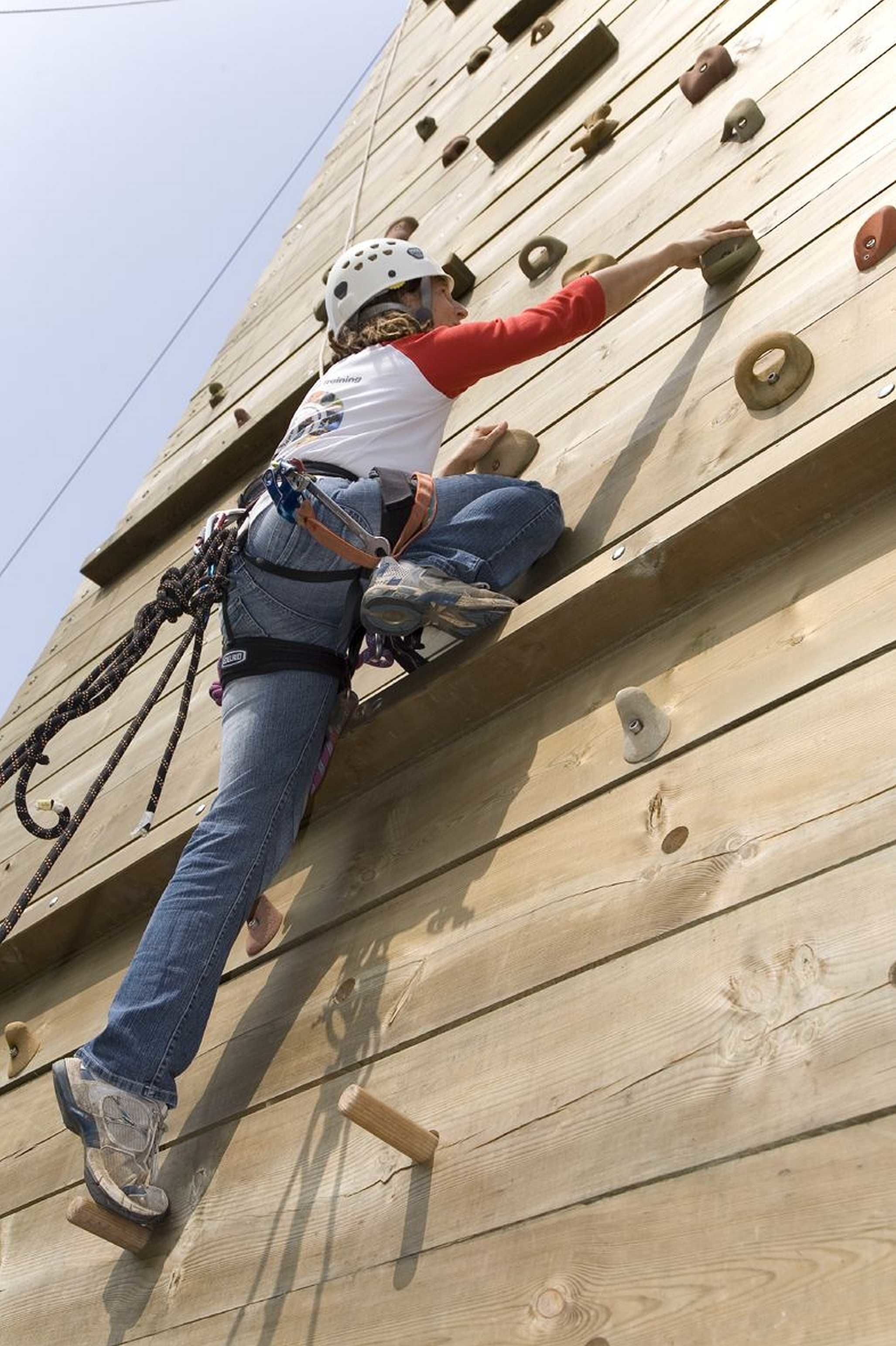 Una persona escalando una pared de madera con puntos de apoyo para manos y pies.