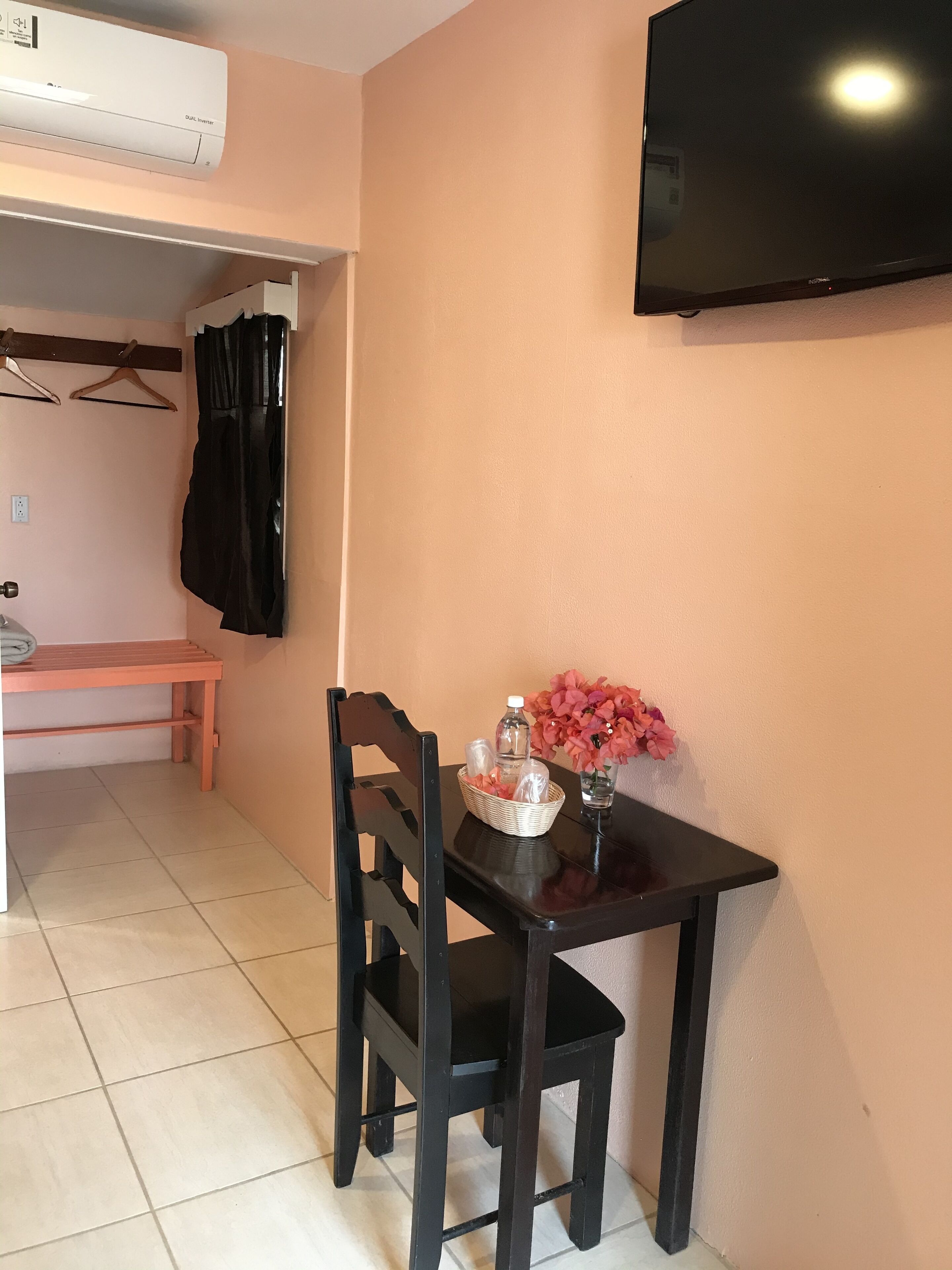 A small room with a table, chair, TV, and a wall-mounted air conditioner.