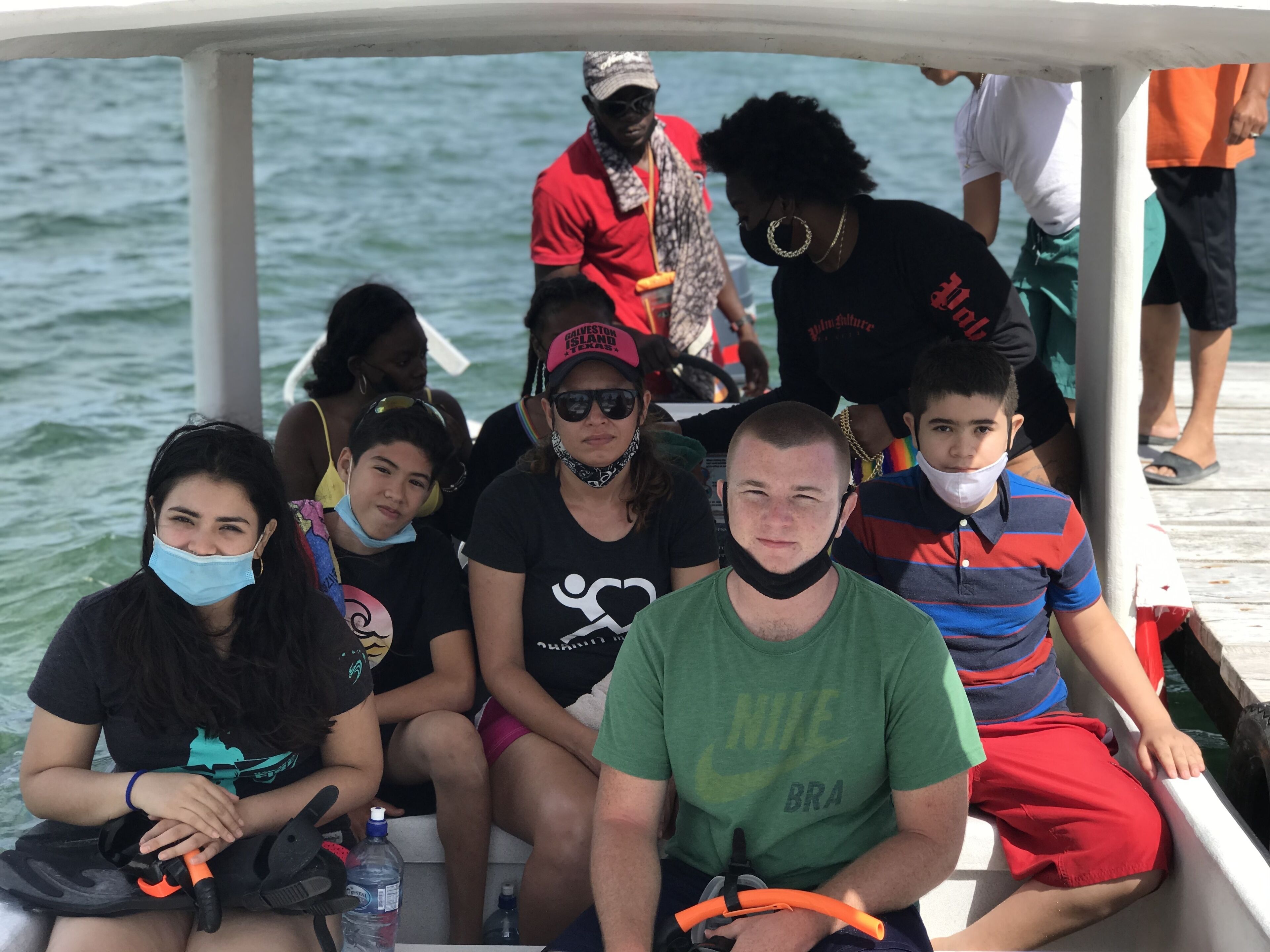 Un grupo de personas en un bote con barandilla y agua de fondo.