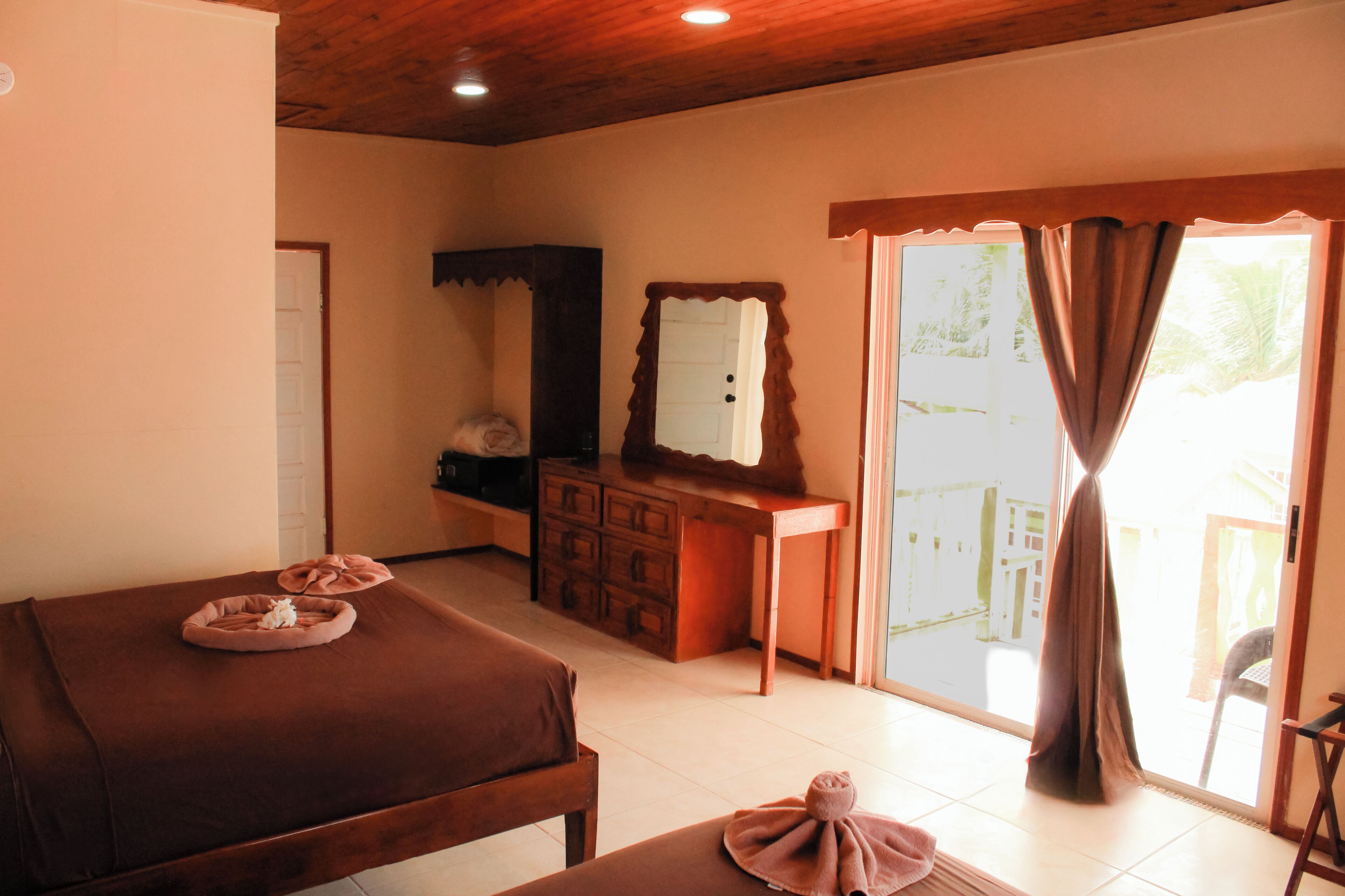 A room with a bed, a dresser, a mirror, and a sliding glass door to the outside.