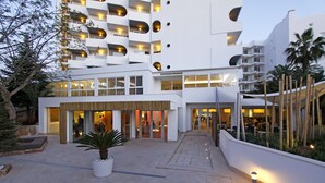 Un hotel moderno con un patio amplio, ventanas grandes y una entrada bien iluminada.