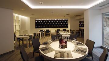 A modern dining area with round tables set for six, equipped with cutlery and wine glasses.