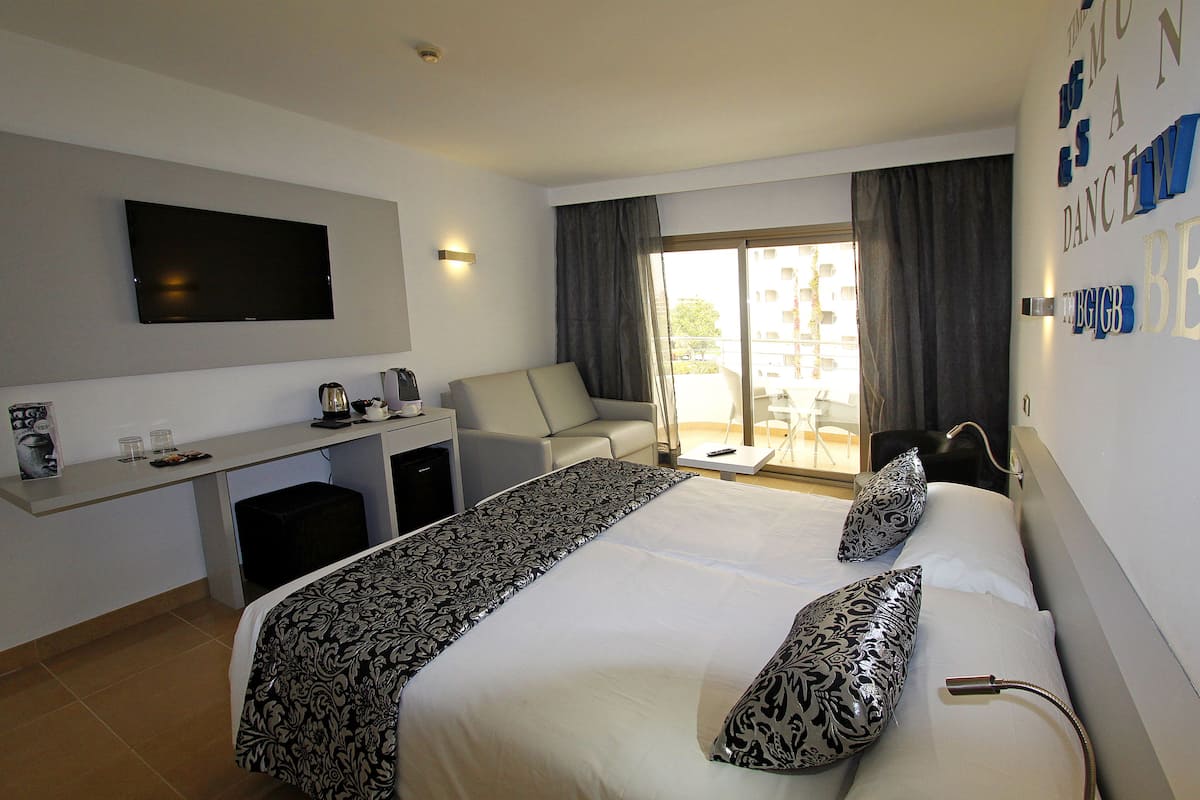Ein Hotelzimmer mit Bett, Schreibtisch, Fernseher und Blick ins Freie.