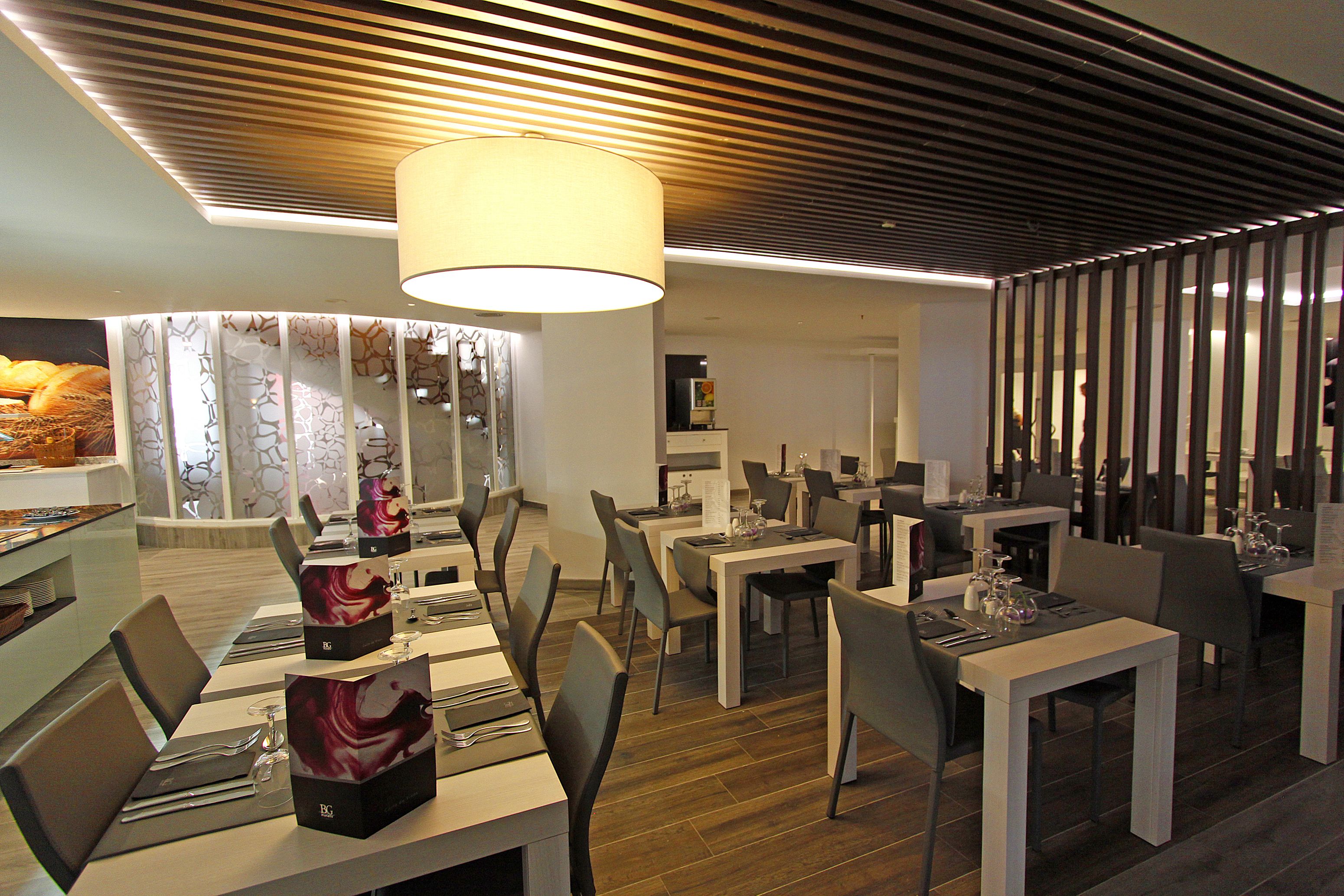 Un restaurante moderno con un diseño contemporáneo, que ofrece diversas opciones de asientos y un área de comedor central con una gran araña.
