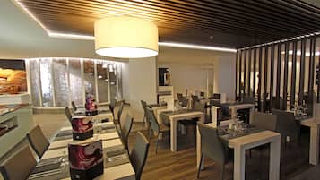 Un restaurante moderno con un diseño contemporáneo, que ofrece diversas opciones de asientos y un área de comedor central con una gran araña.