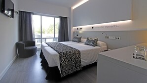 Una habitación de hotel moderna con una cama grande, una silla, un escritorio y un televisor.