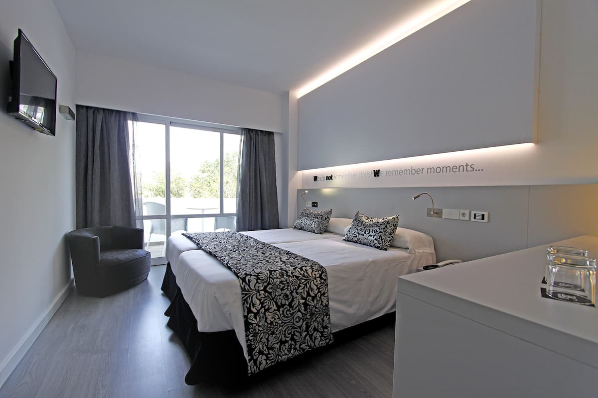 Ein modernes Hotelzimmer mit einem großen Bett, einem Sessel, einem Schreibtisch und einem Fernseher.